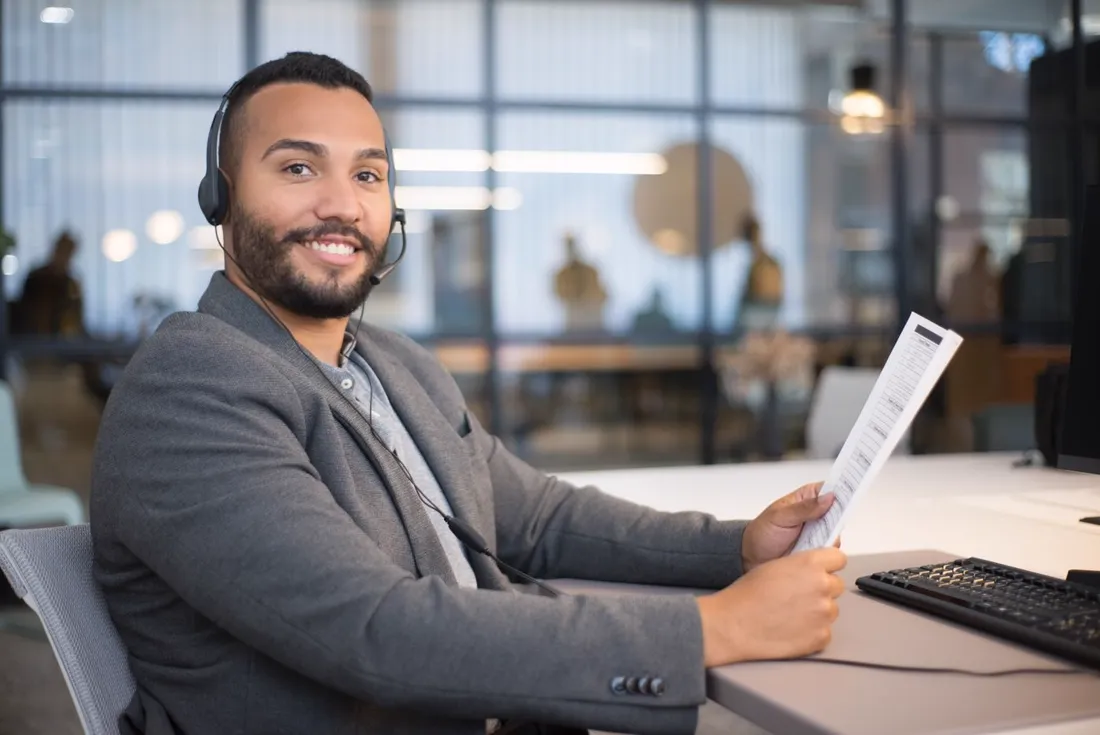 Beispielbild: Mitarbeiter mit Headset am Schreibtisch